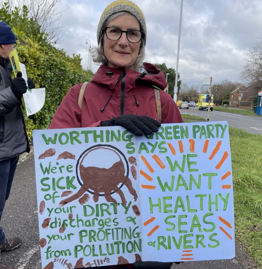 Claire Hunt holds a sign protesting the sewage in our seas