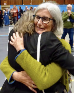 Claire Hunt hugging fellow Green campaigner while a supporter looks on and claps